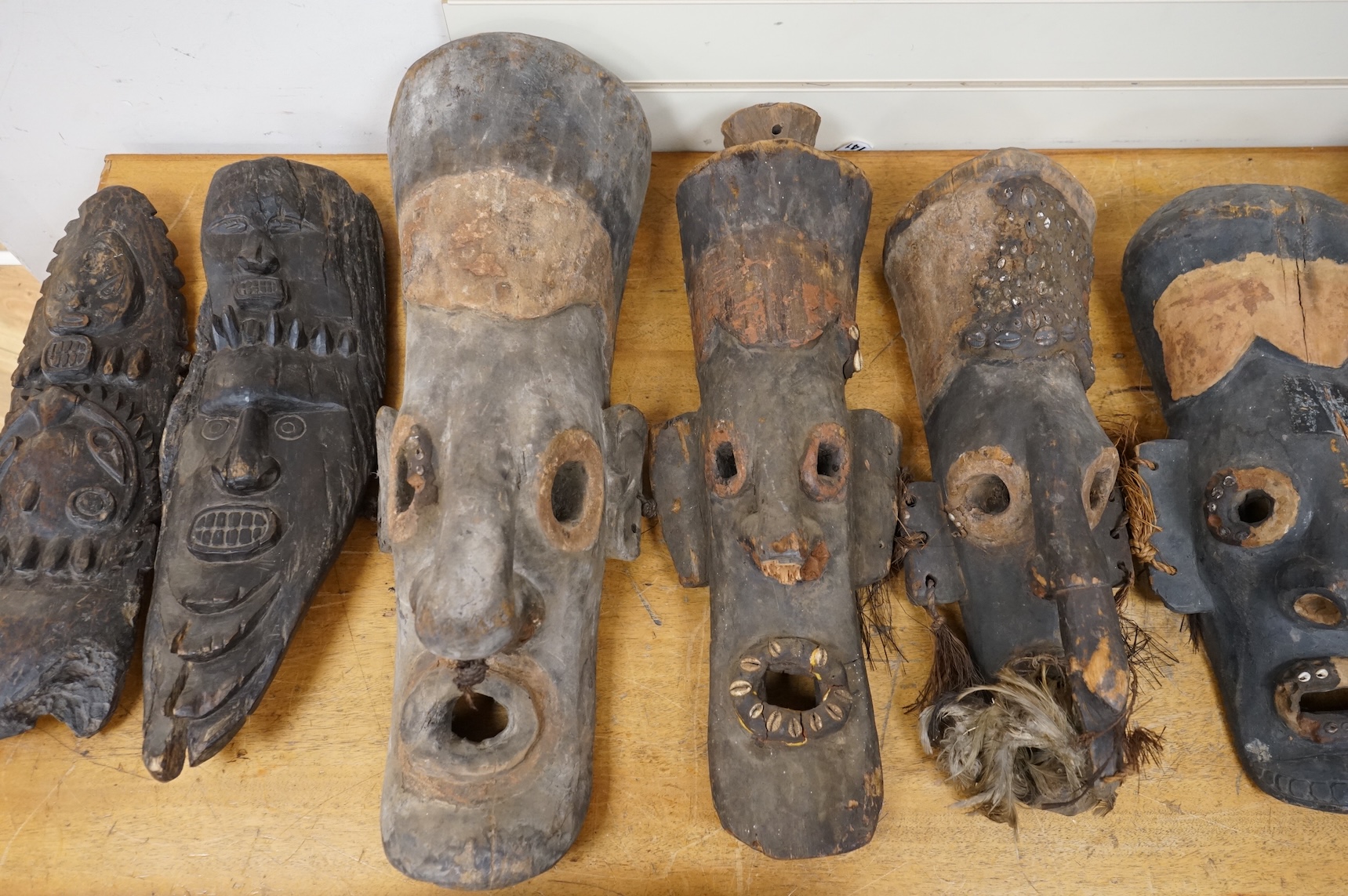 Papua New Guinea Septik River, a collection of five similar carved wooden masks of elongated form, applied in places with shells and two smaller masks with double face carving. Largest 80cm high.